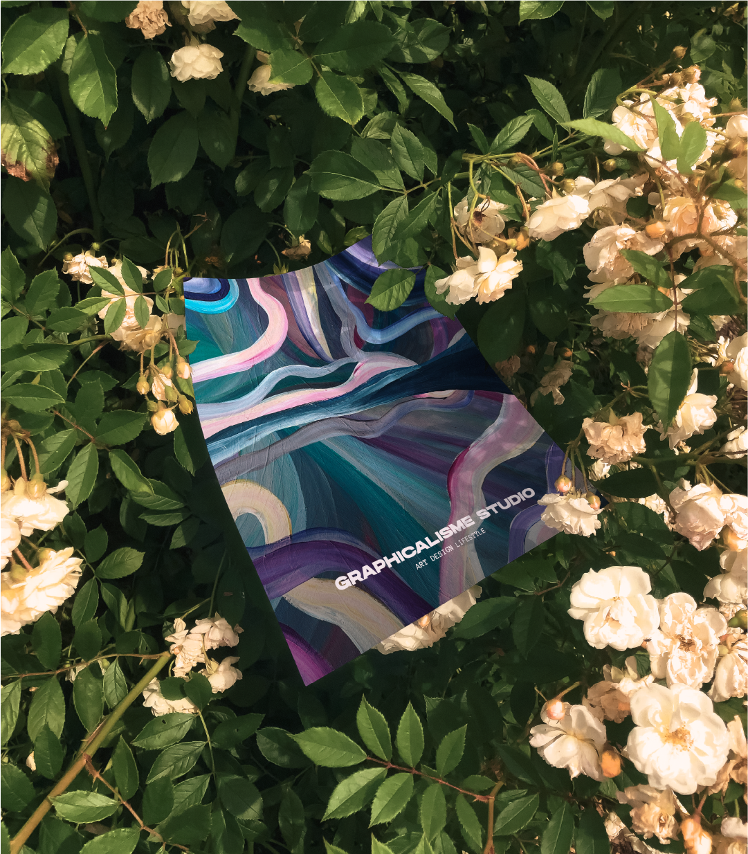 Une affiche colorée avec des lignes abstraites, posée parmi des fleurs blanches et des feuilles vertes.