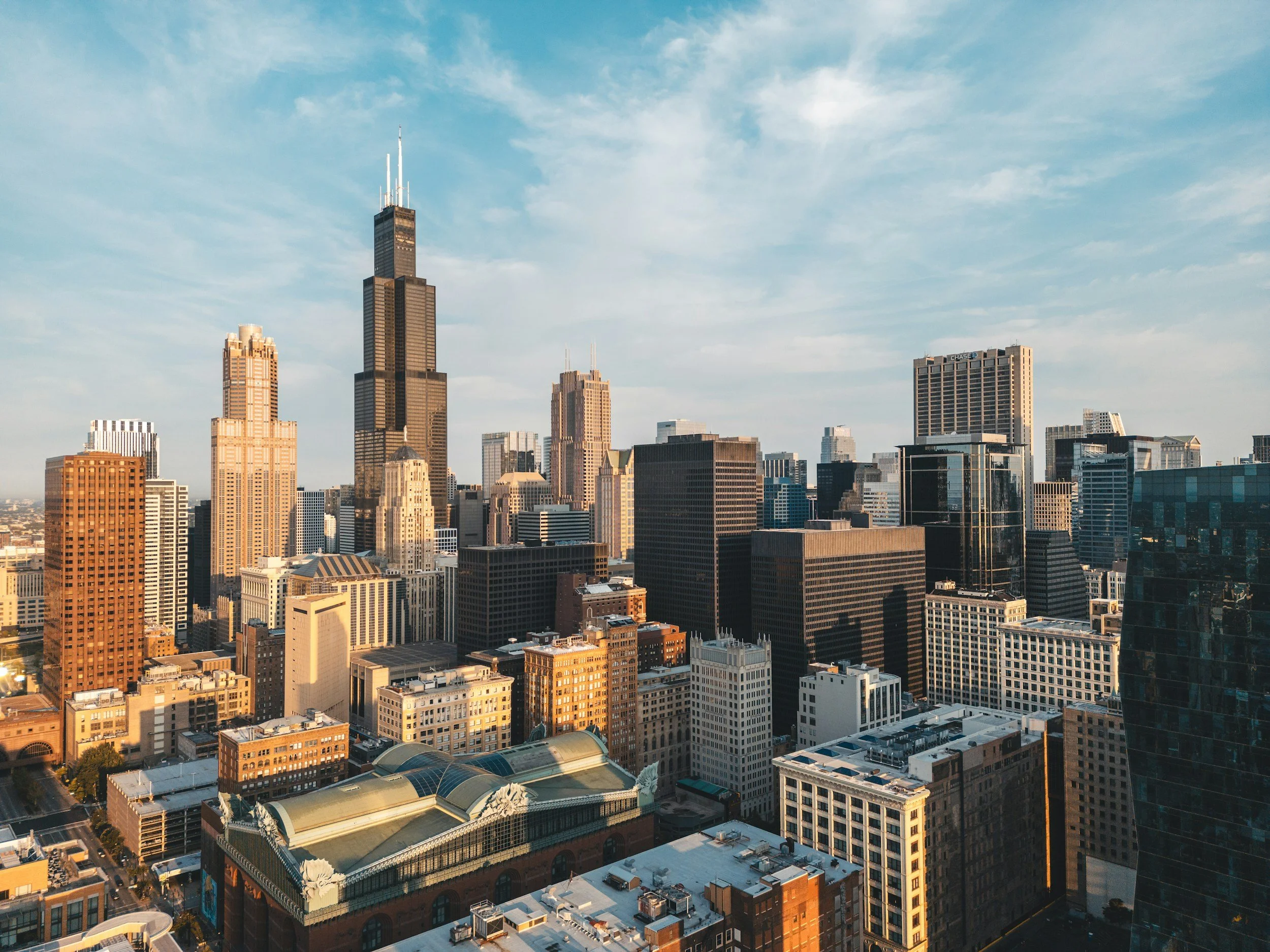 The Chicago city skyline with tall skyscrapers and buildings under a partly cloudy sky during daytime. This is the headquarters of Hudson Street Ventures