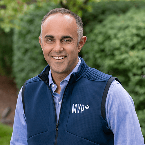 Michael Aubrey, Advisor at Hudson Street Ventures. A smiling man in a blue vest with 'MVP' logo standing outdoors with green foliage in the background.