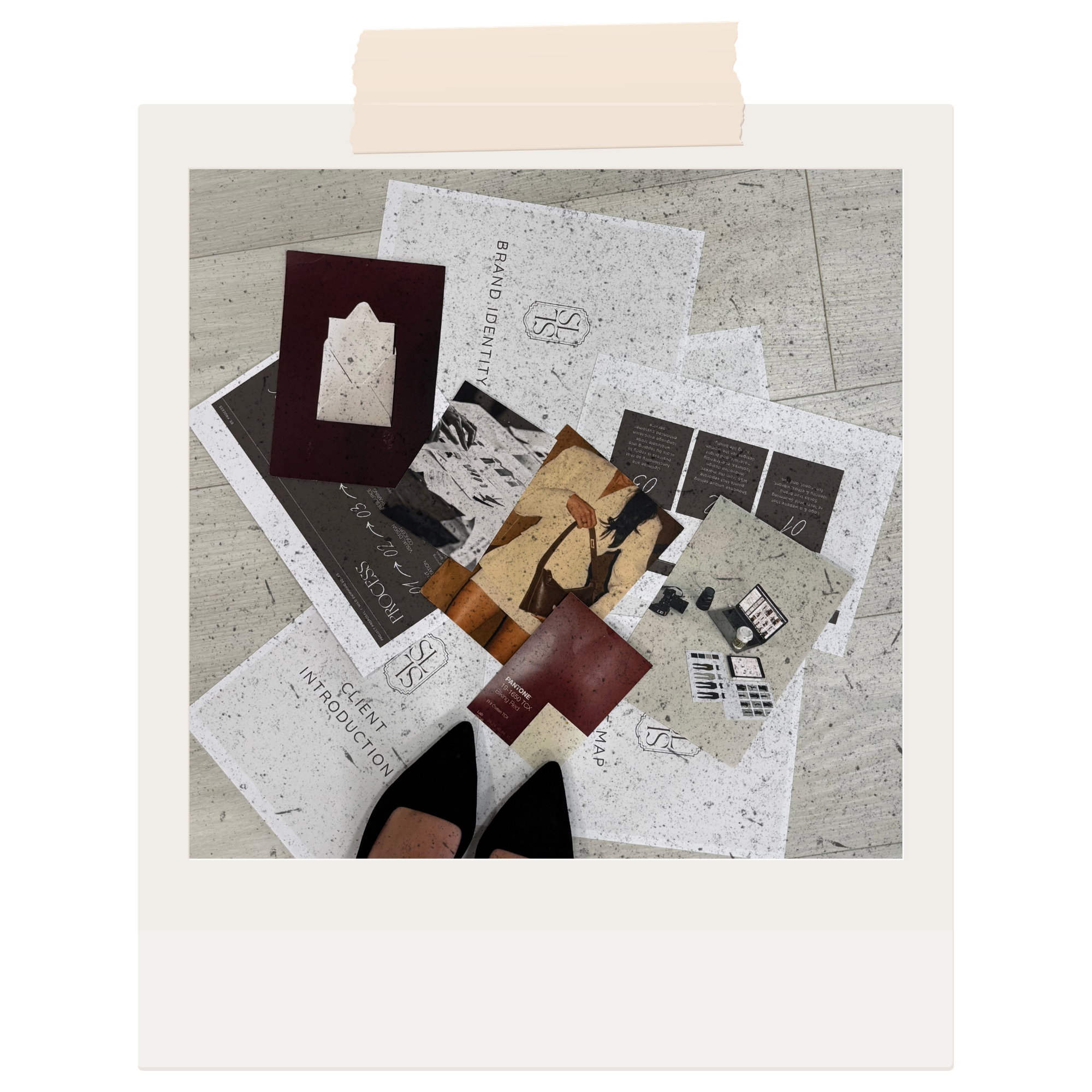 A collection of printed materials, including a brand identity guide, on a light-colored wooden floor.