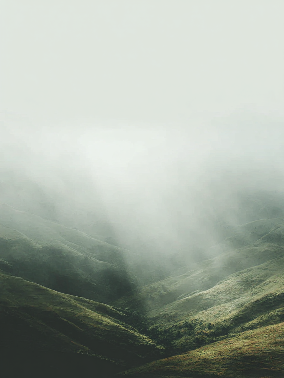 Green foggy mountains with mist covering the peaks and valleys.