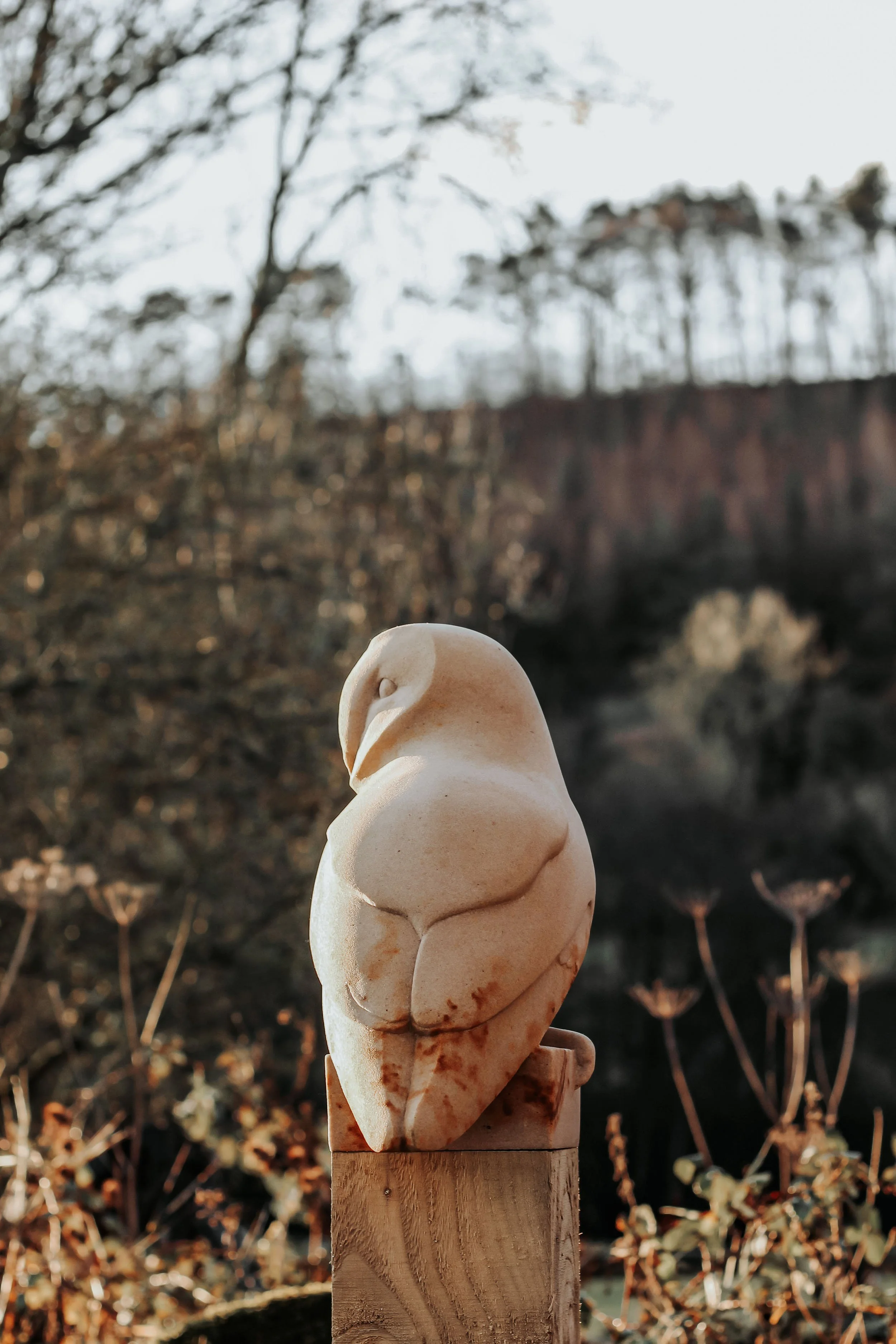 An owl sculpture carved in stone perched on a wood post