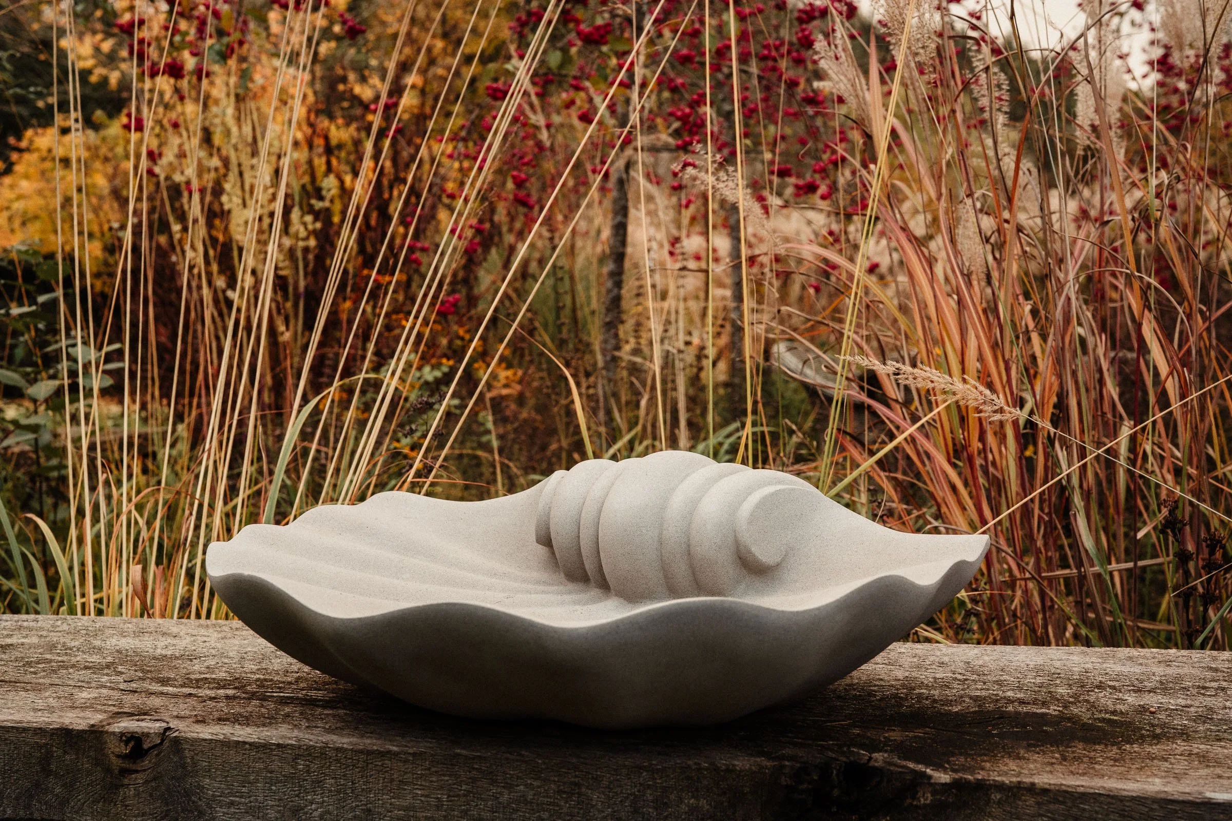 Sculptural shell-shaped birdbath carved in natural stone
