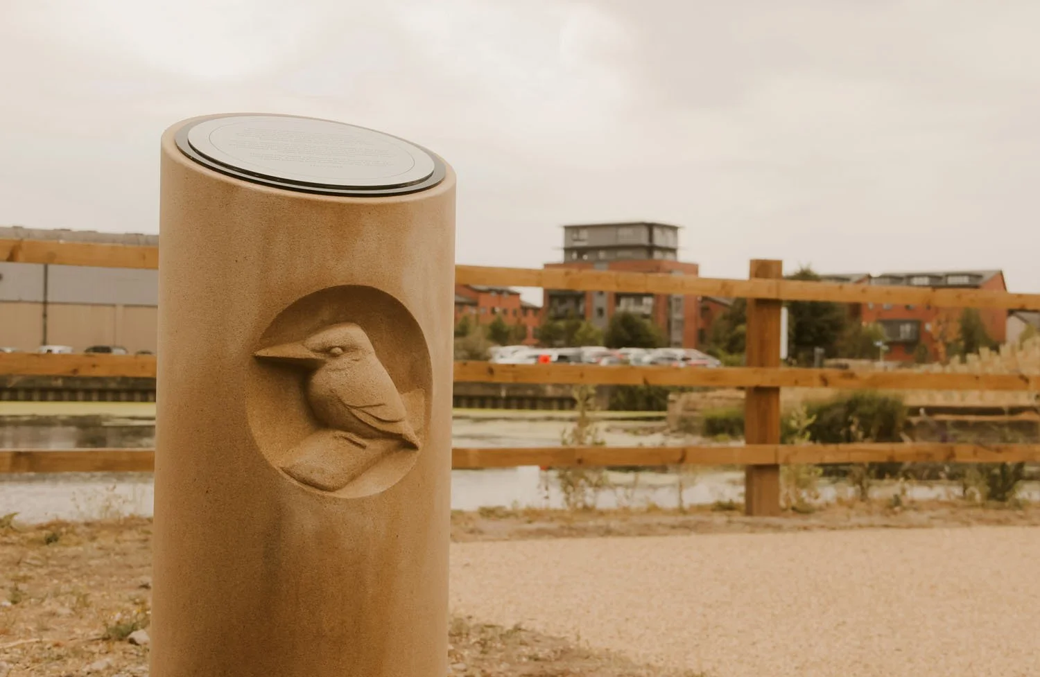 Stone column carved with a Kingfisher perched on a branch - part of the Arup Architects River Aire Memorial Walk commission