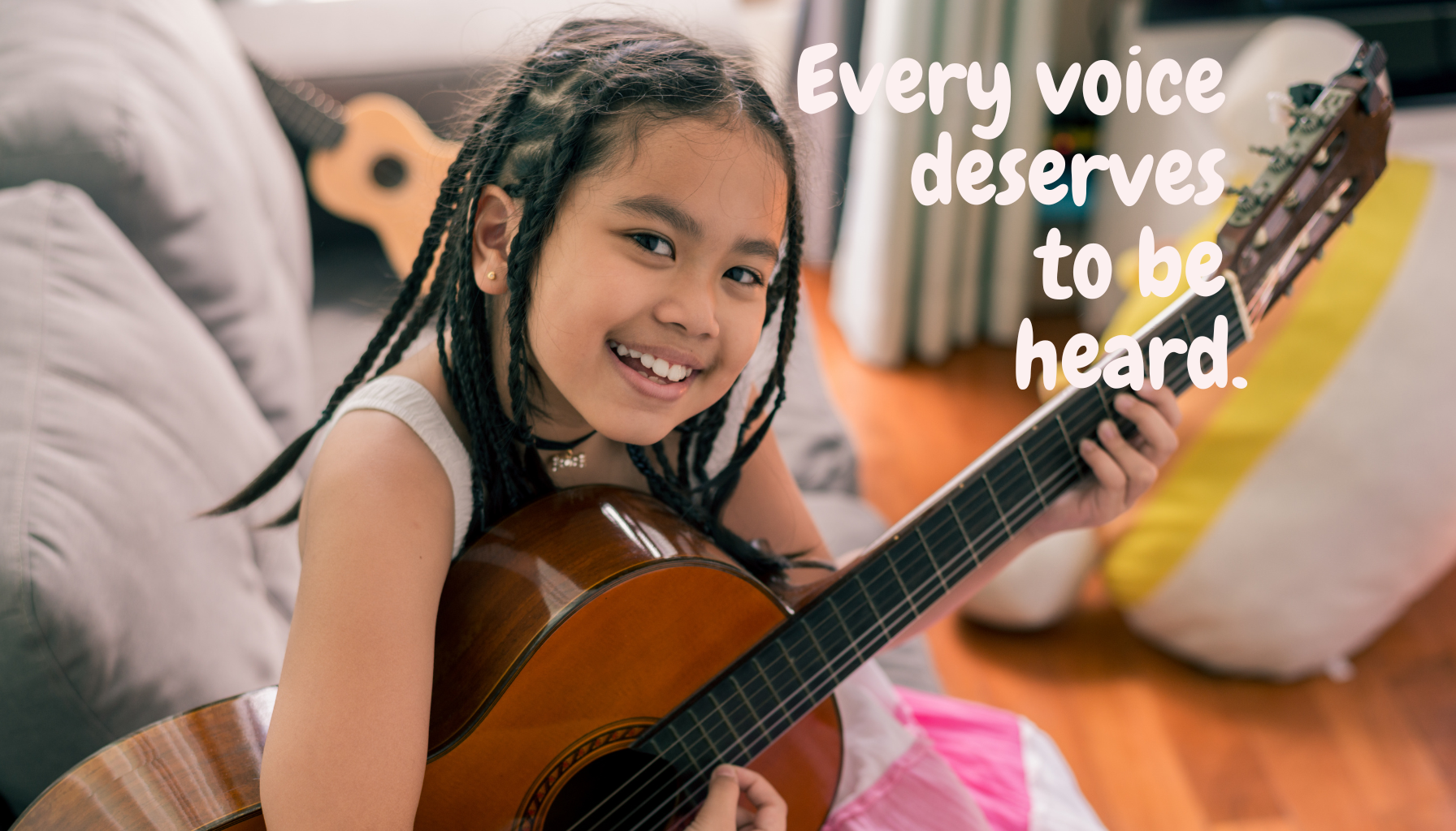 A young girl holds a guitar and smiles at the camera.