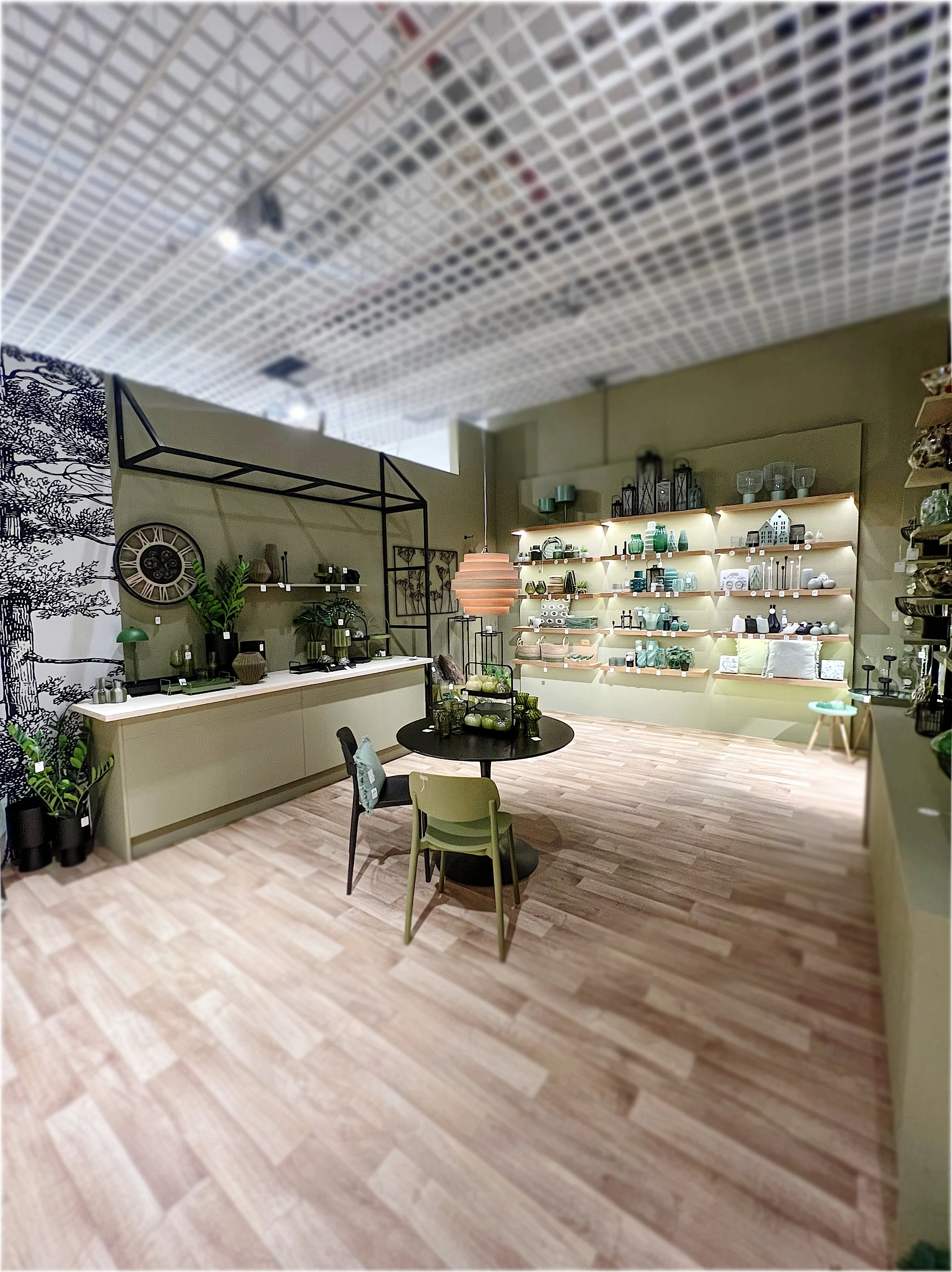 Inneneinrichtung eines Wohnaccessoires-Shops mit grün und schwarz gestalteten Regalen, Tischen und Dekorationen.