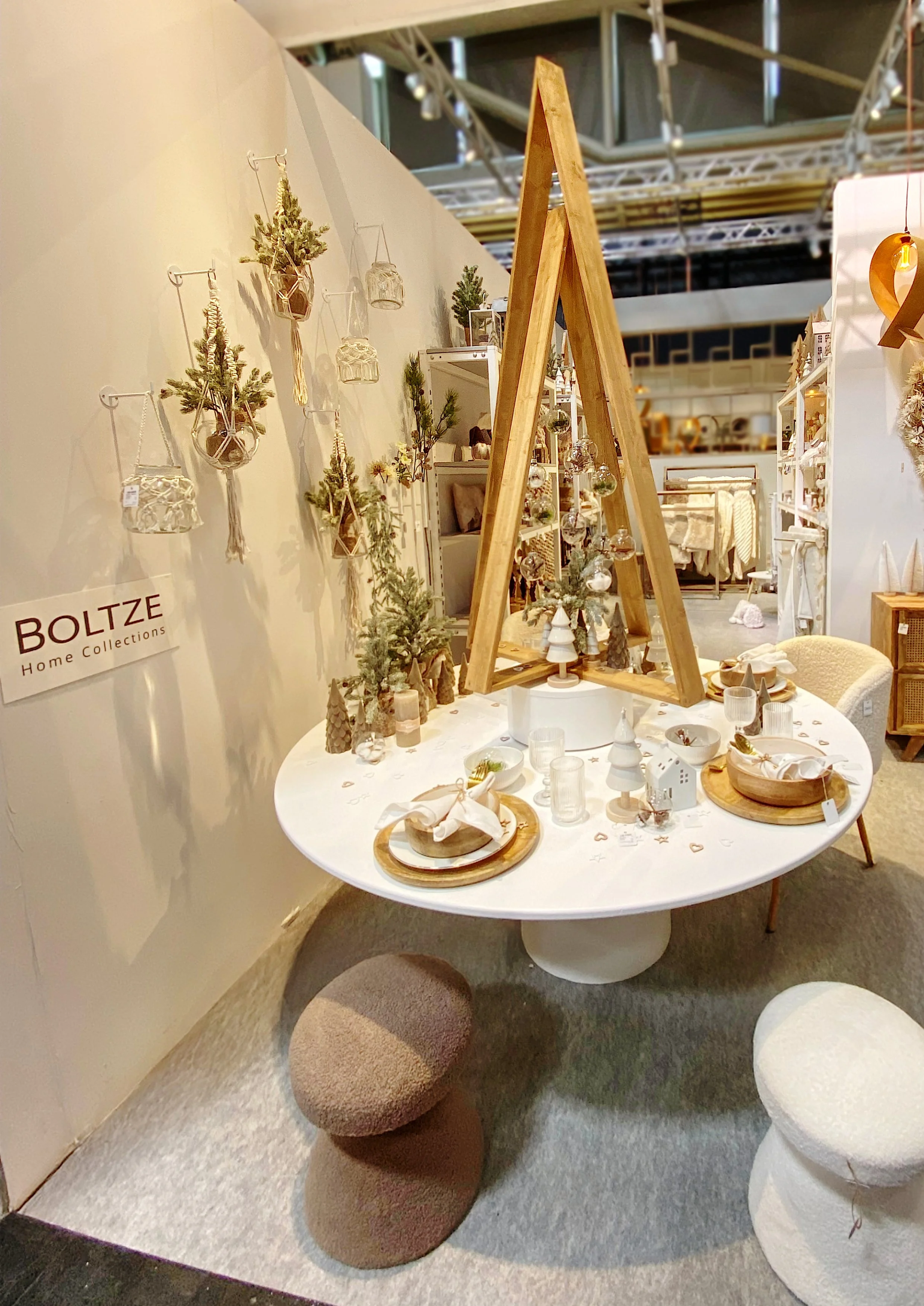 Jahresdeko-Tisch mit weihnachtlichen Elementen, Holzdekorationen, kleinen Weihnachtsbäumen und Stabkerzen in einem Möbelgeschäft.