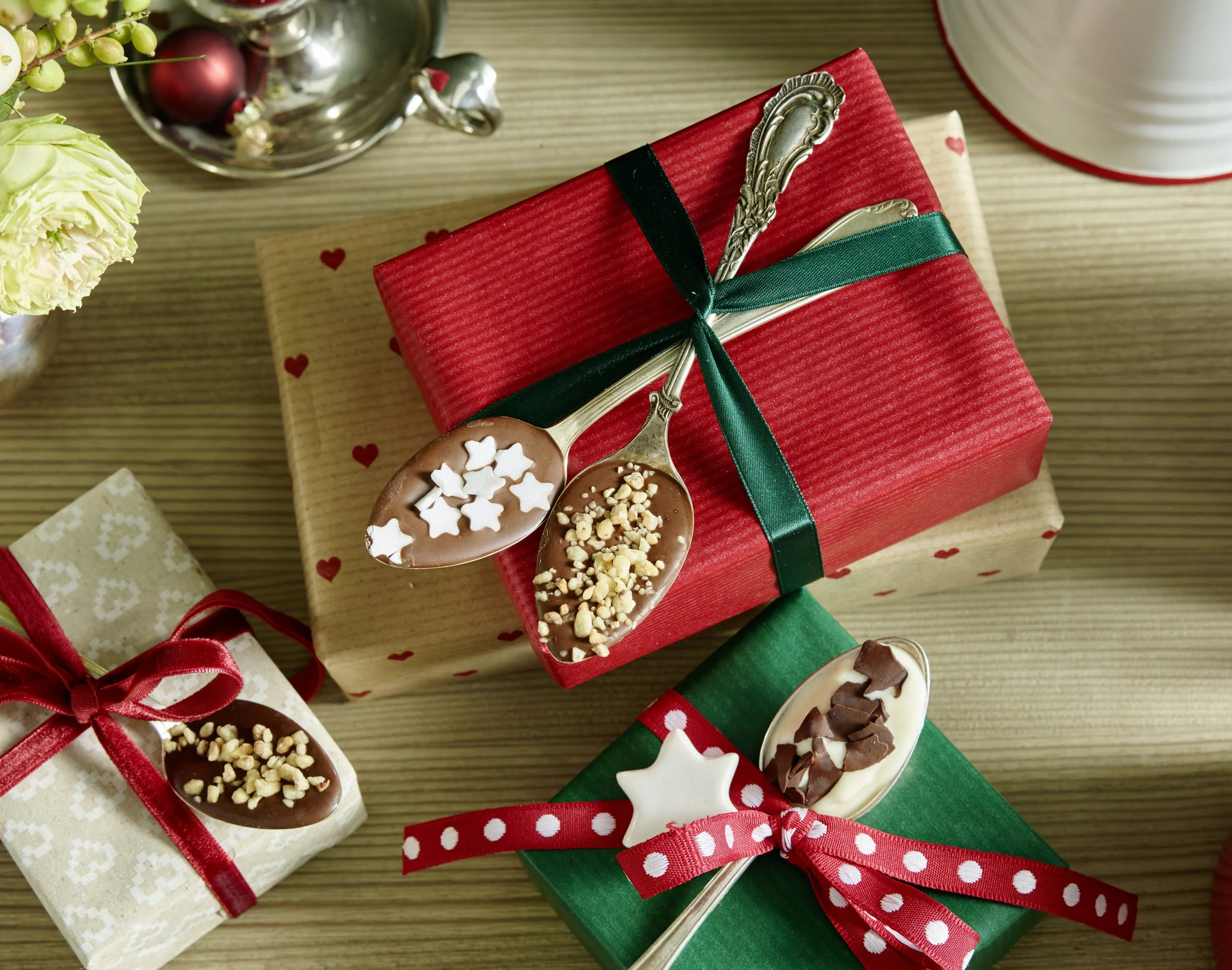 Geschenkboxen und Löffel mit Schokolade und Dekorationen auf Holztisch, festliche Stimmung, Weihnachten.