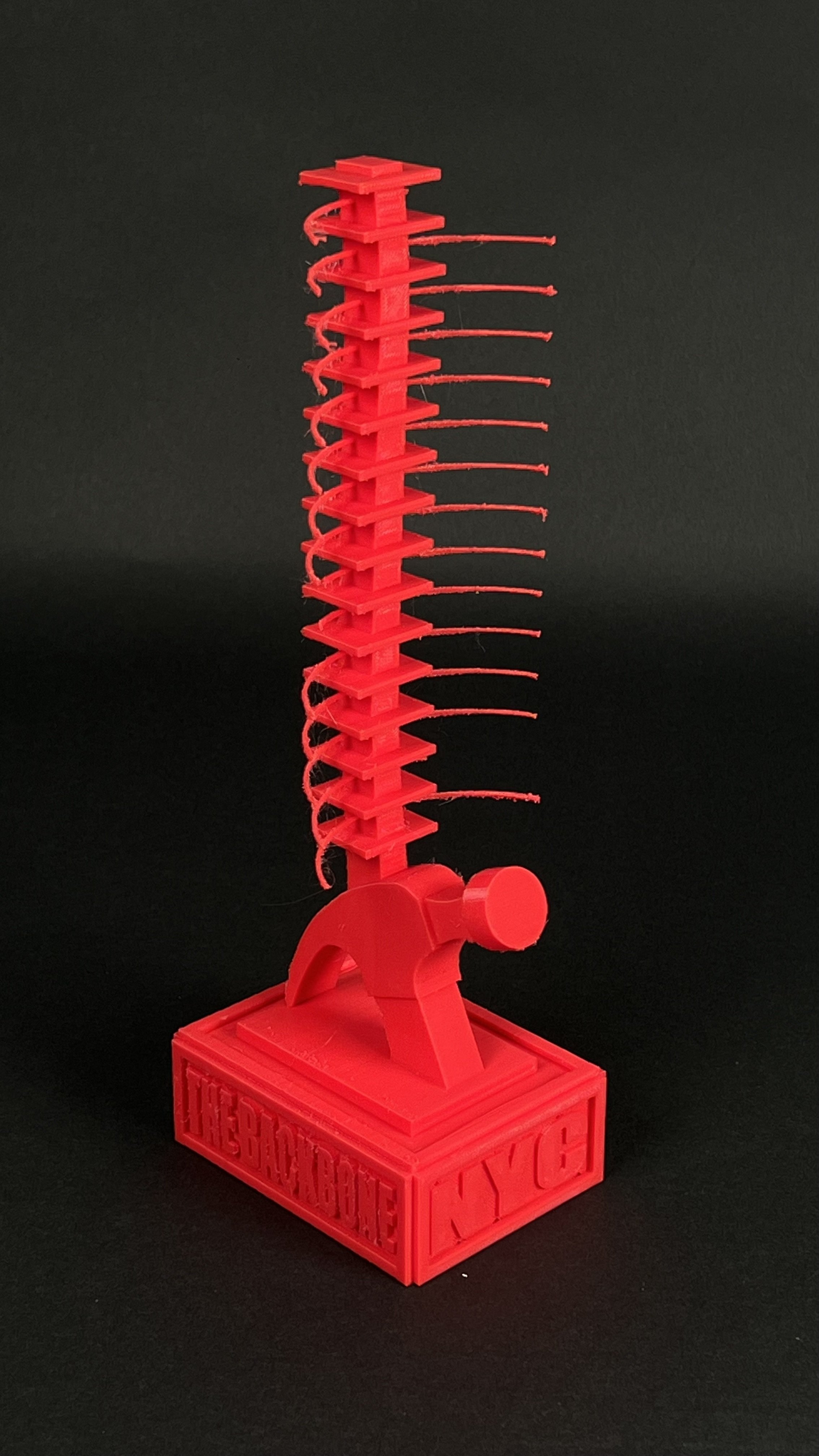 Red 3D-printed Ferb's invention from Phineas and Ferb, resembling a towering structure with a base labeled 'CY' and 'FERB,' and a long vertical section with curved horizontal elements.