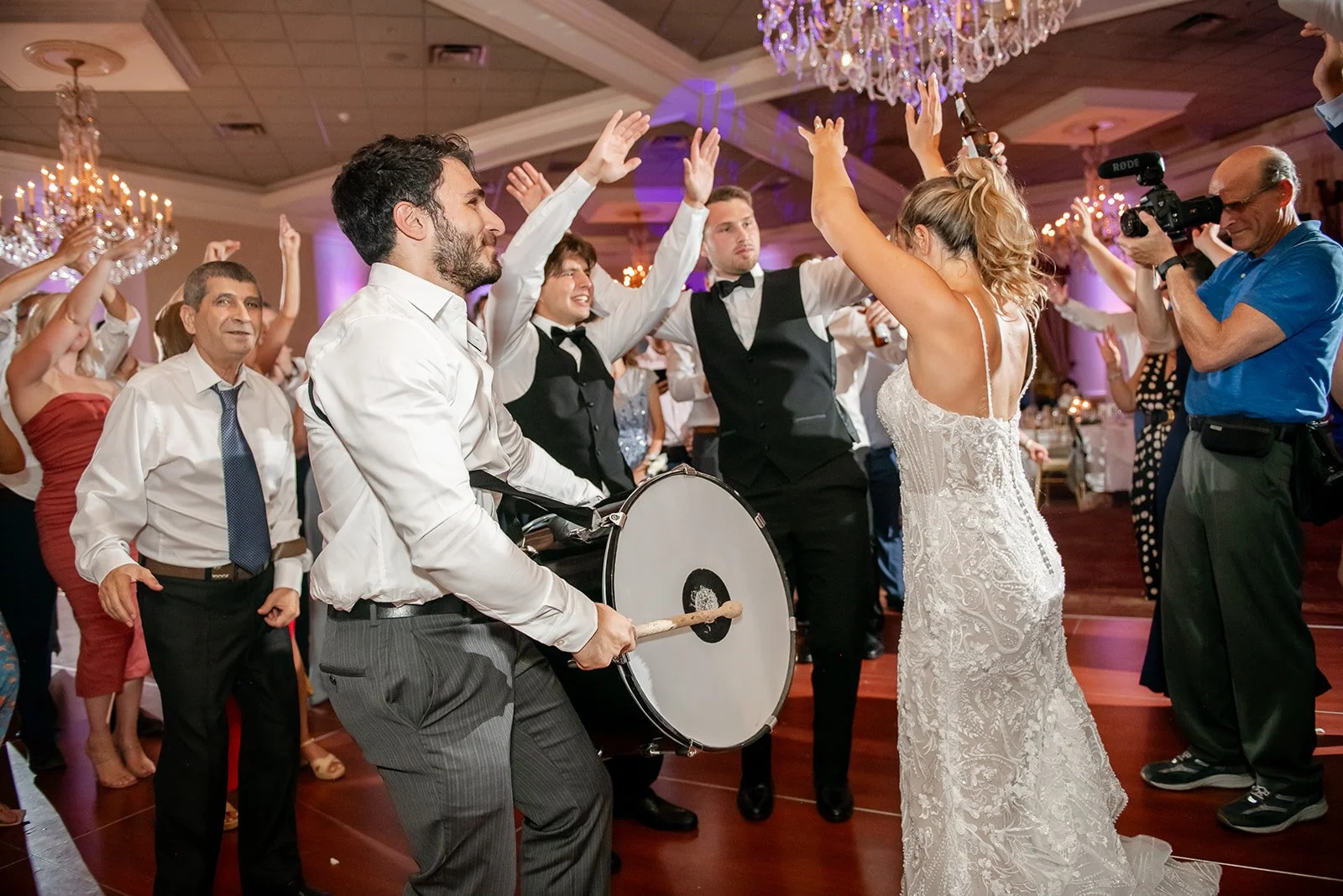 People dancing and celebrating at a wedding reception with a drummer and a photographer capturing the moment. DJ MICHAEL KHOURY - BUFFALO ROCHESTER DJ
