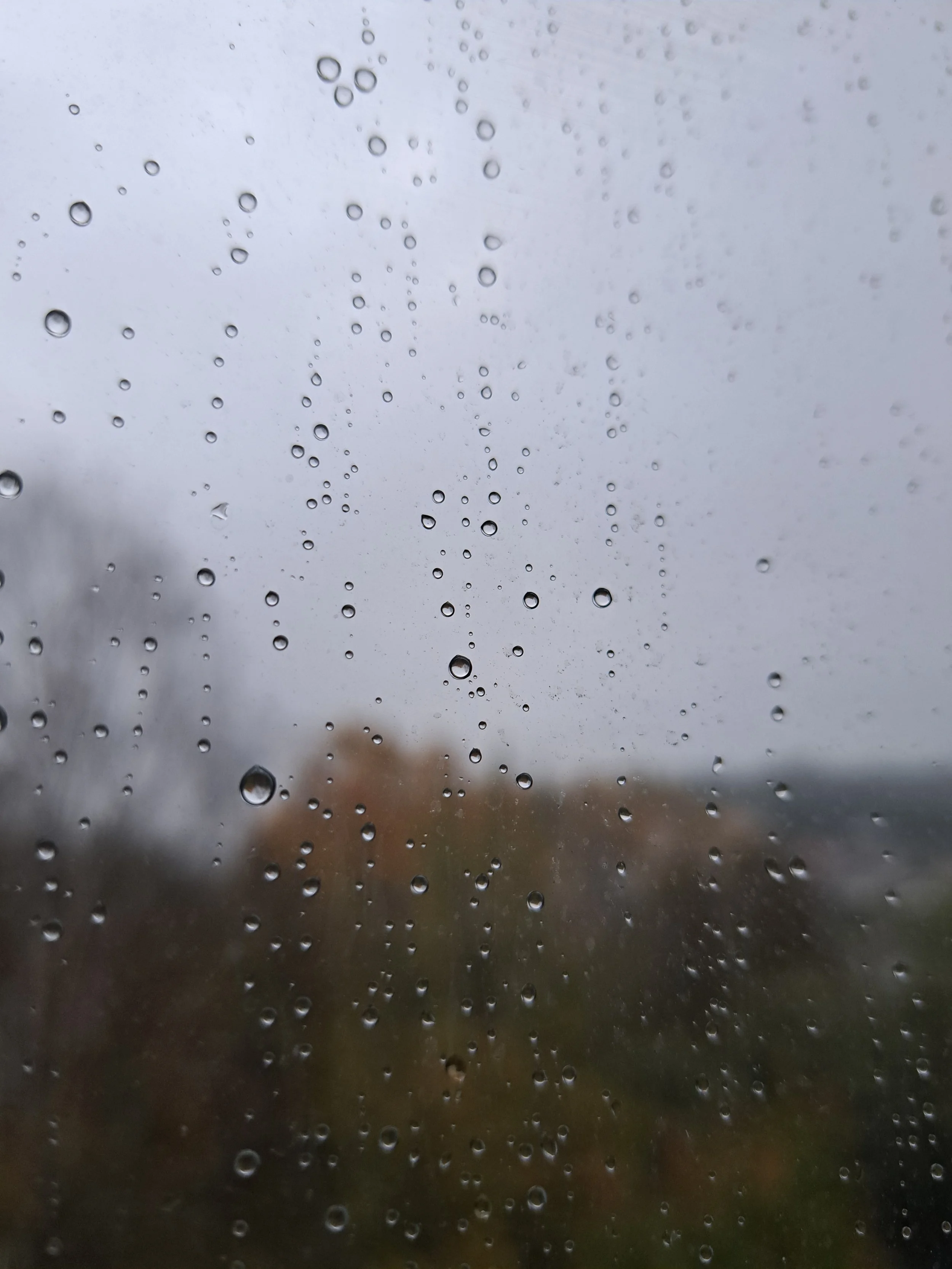 Ventana con gotas de lluvia en un día nublado y lluvioso.