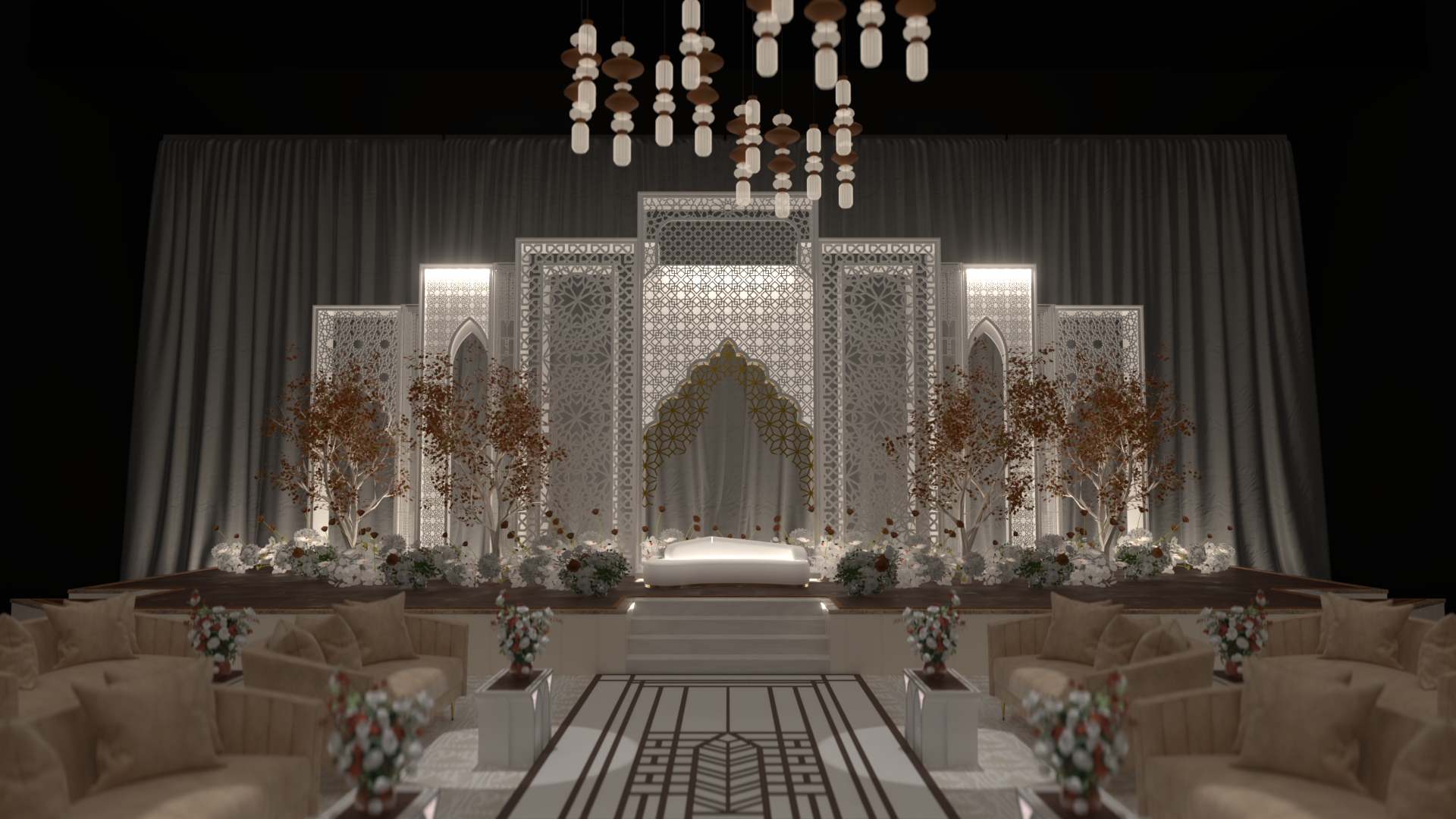 Elegant indoor event space with a stage featuring a white backdrop, decorative screen panels, trees, floral arrangements, and seating area with beige sofas and vases of flowers.