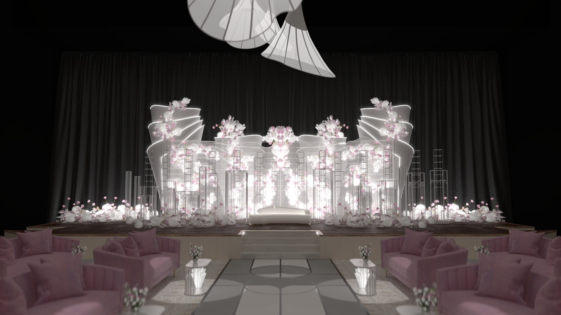 Elegant event stage with white and pink floral arrangements, illuminated backdrop, and pink velvet sofas at the front.
