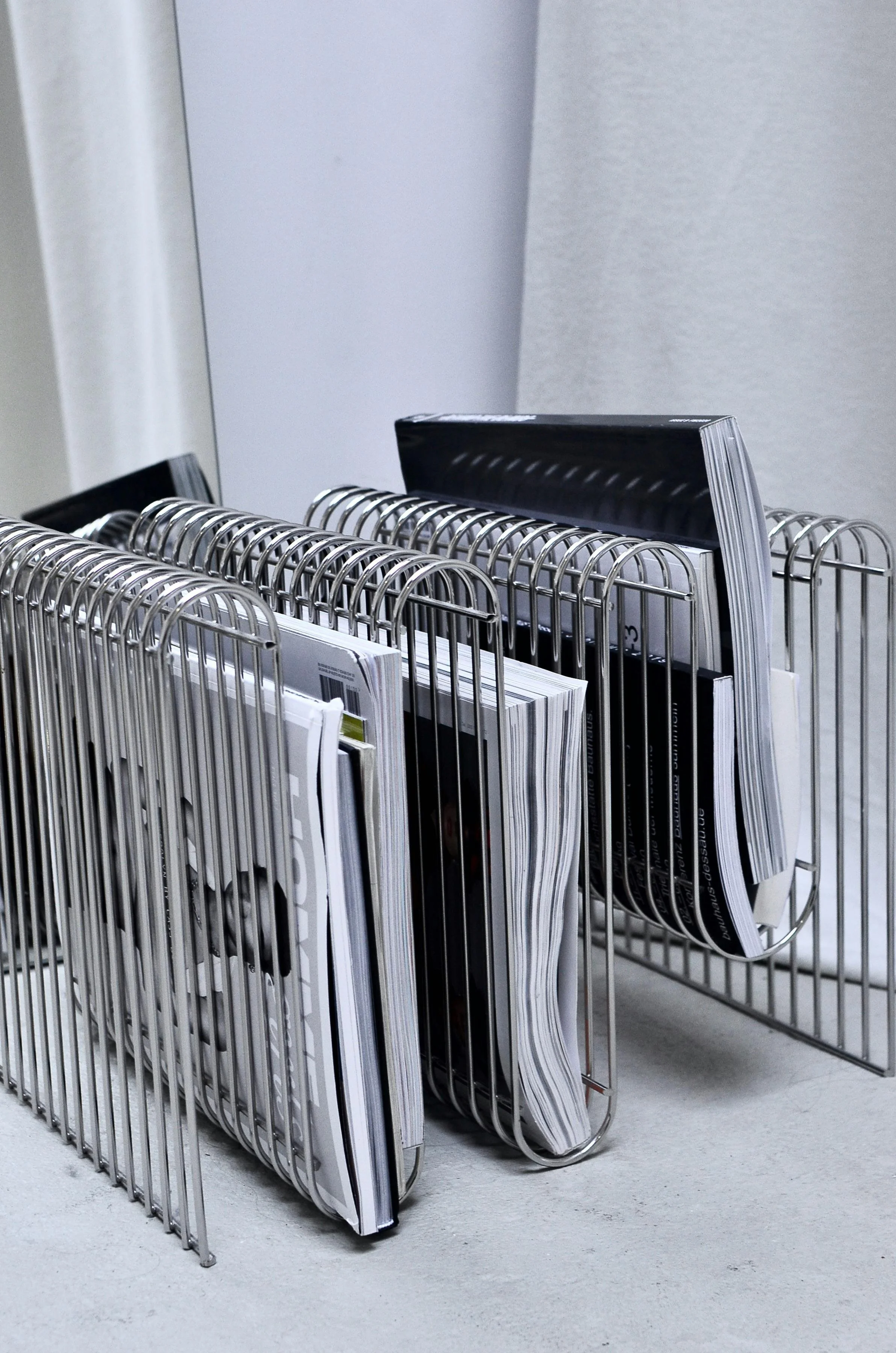 Desk organizer with metal wire compartments holding magazines and documents.