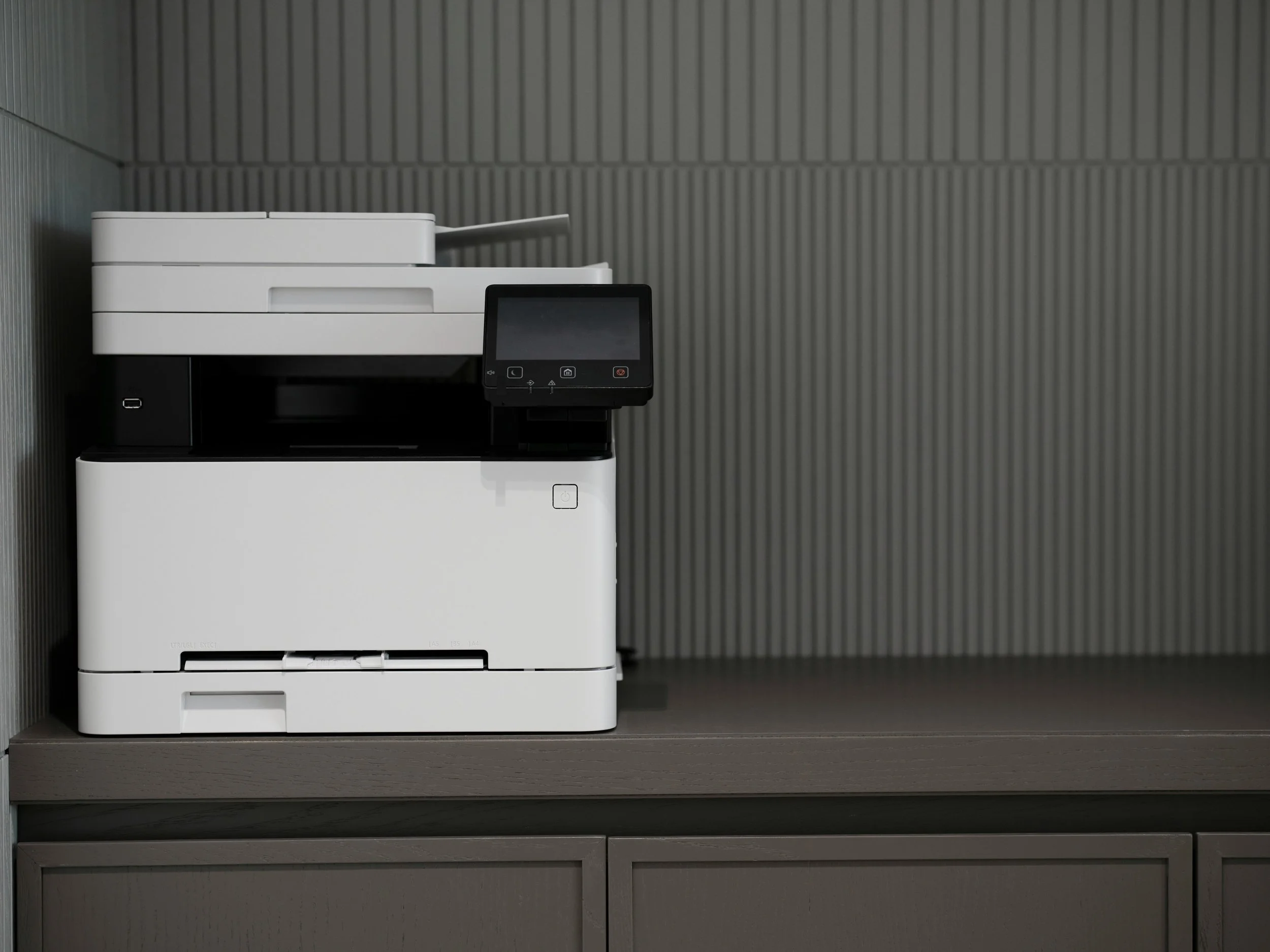 white multifunction printer on a gray cabinet in an office setting