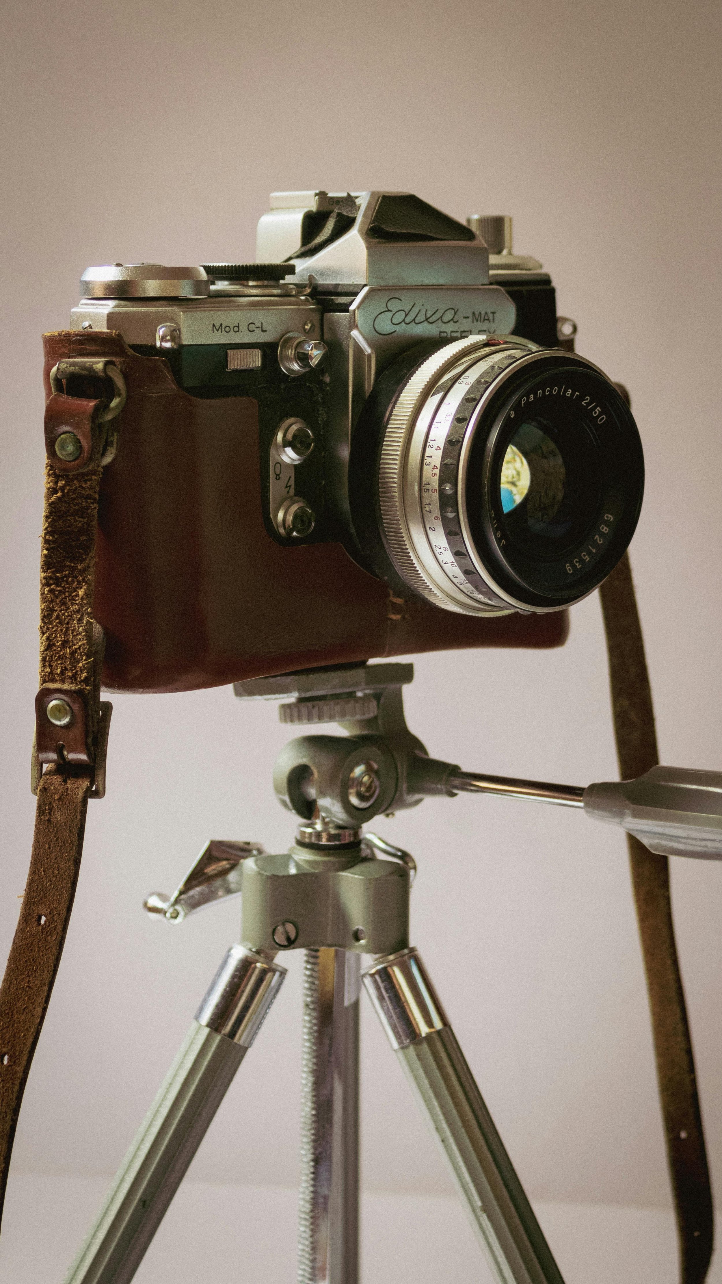 Vintage camera mounted on a tripod with a leather cover.