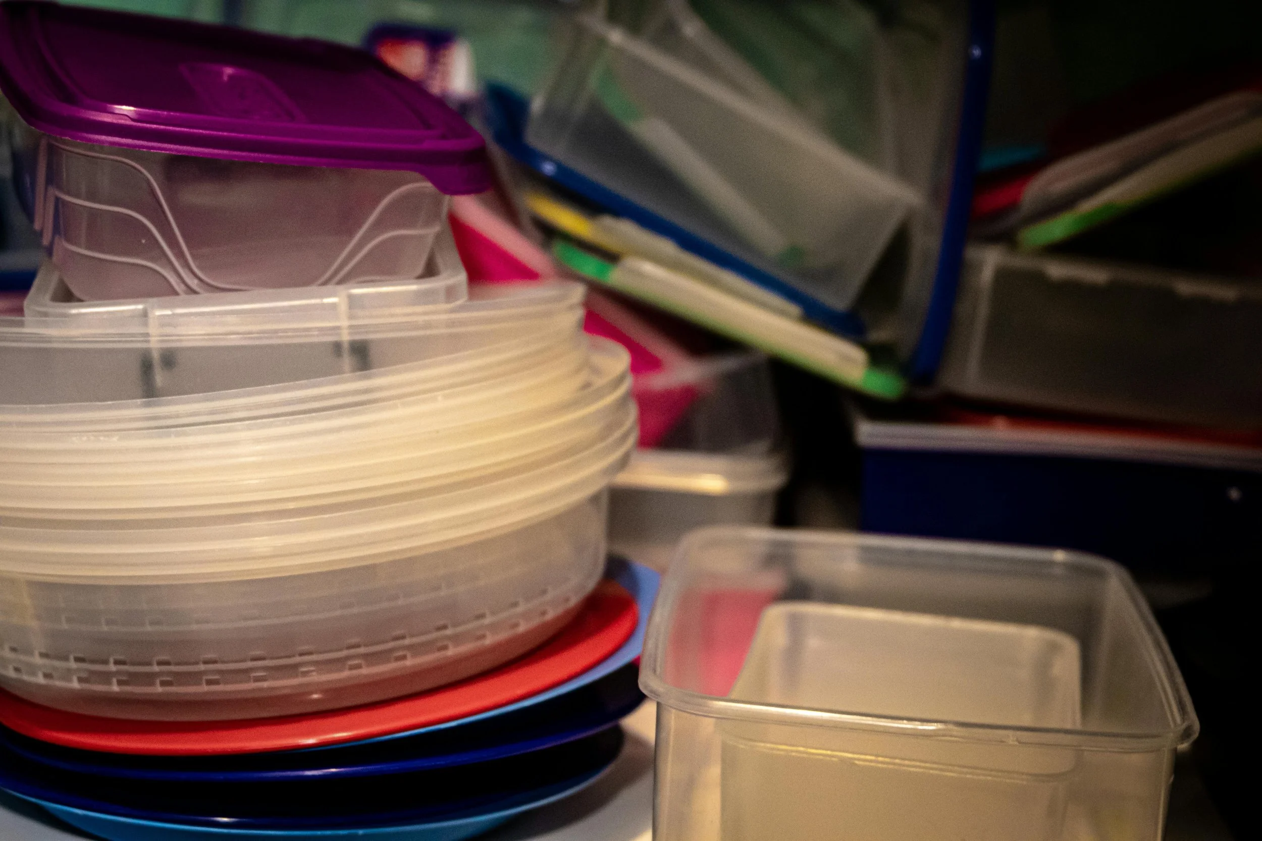 Stacked colorful plastic containers and lids in an organized storage area.