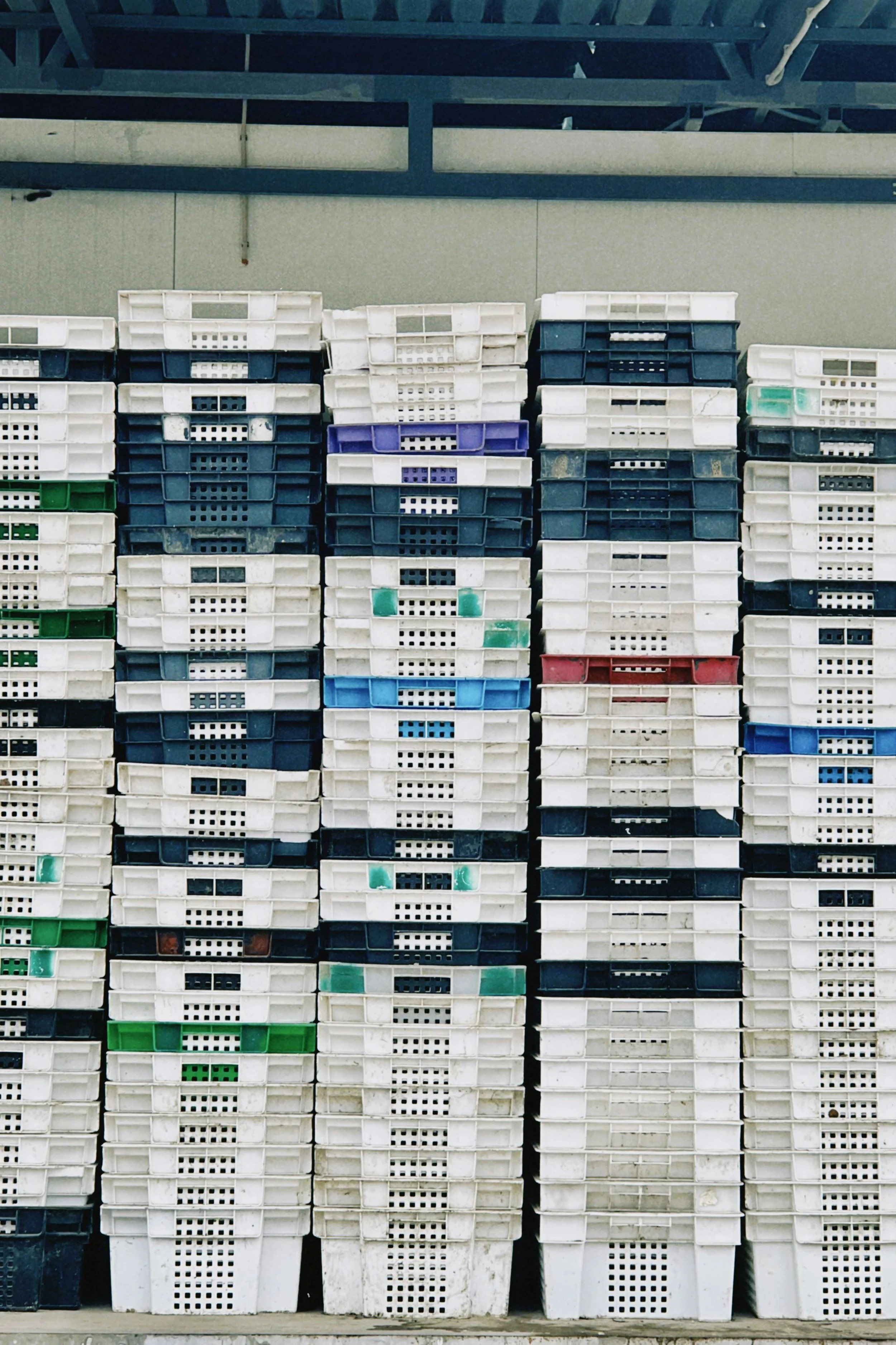 Stacked plastic storage bins in various colors in a warehouse.