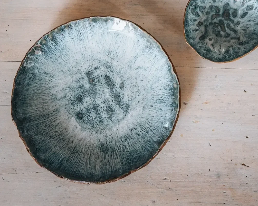 Deux assiettes en céramique avec des motifs abstraits de couleur bleue et blanche sur une surface en bois clair.