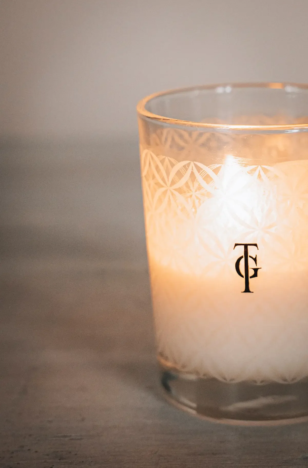 Bougie allumée dans un verre décoratif avec initiales TF.