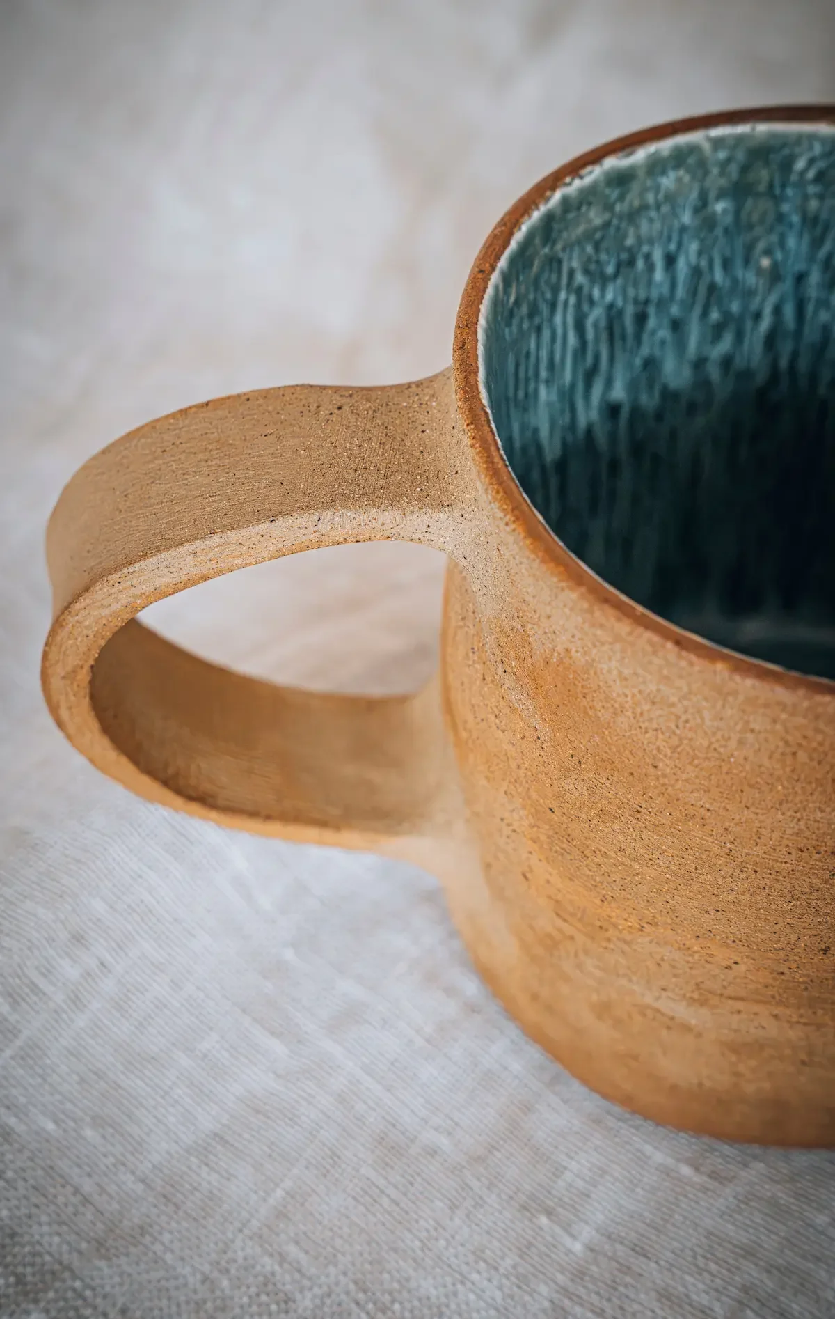 Une tasse en céramique beige avec un intérieur bleu foncé, vue rapprochée.