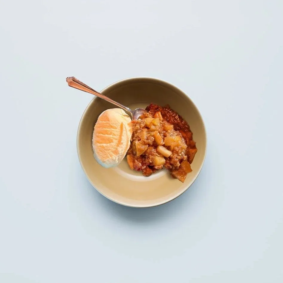 Baked dish with sliced almonds on top, in a rectangular white ceramic baking dish placed on a wooden surface.