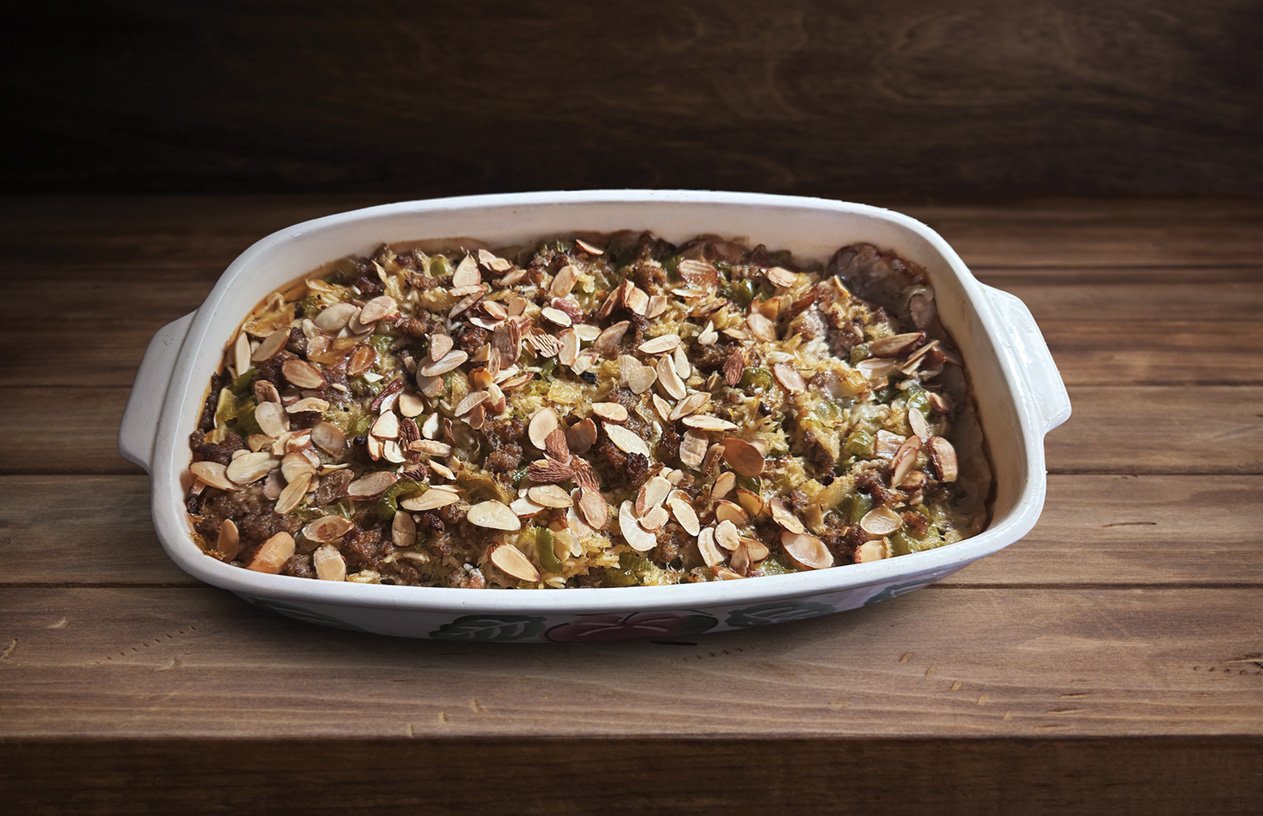 Baked dish topped with sliced almonds on a wooden surface