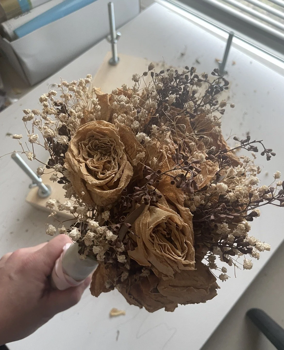 A dried wedding bouquet from years ago being transformed into artwork.