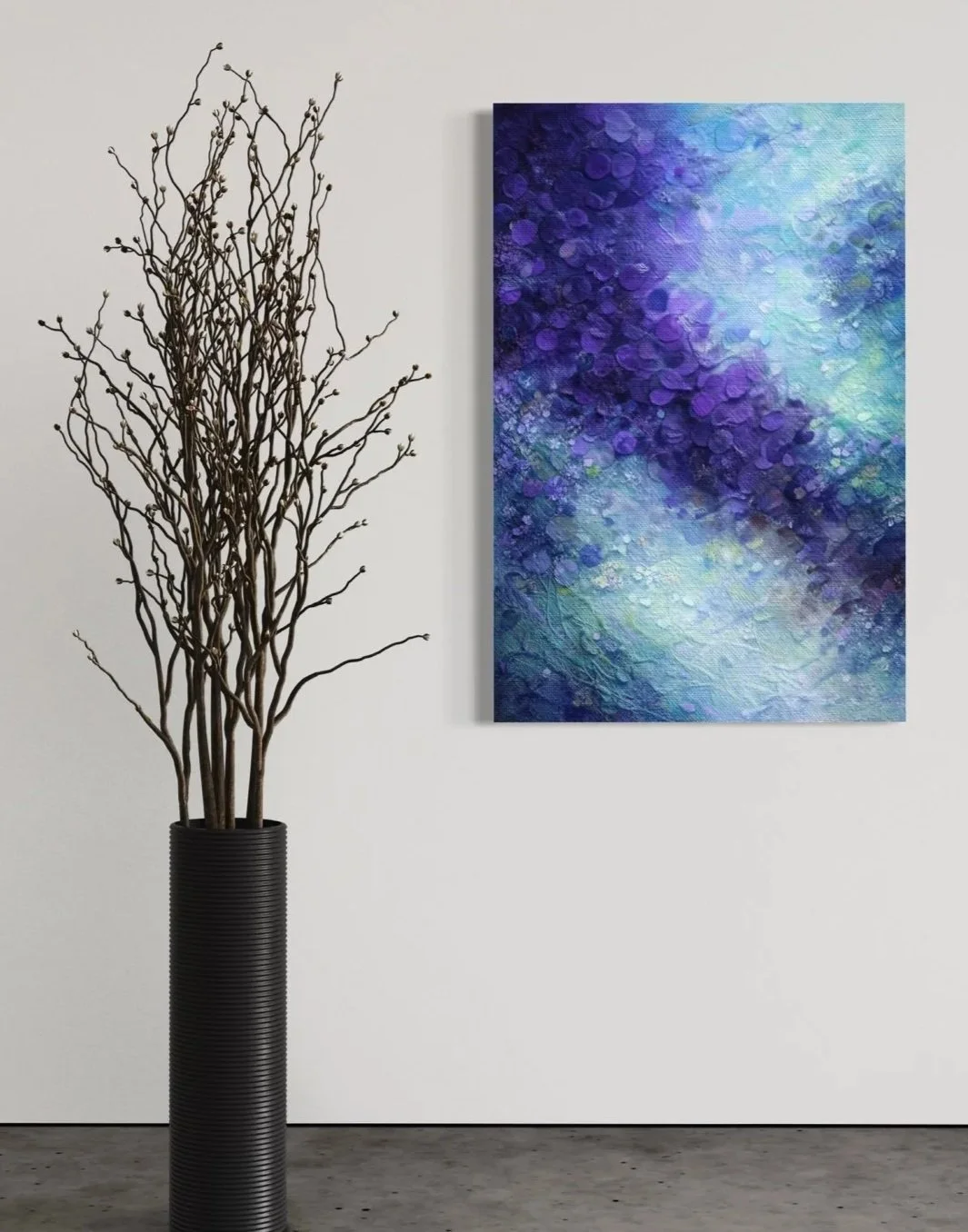 Floral preservation in Columbus, Ohio that transformed into a minimalist interior scene with a tall black vase containing bare, twisting branches, positioned beside an abstract blue and purple painting hung on a white wall.