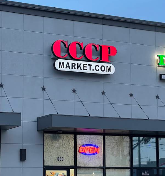 Sign on a building displaying 'CCCP Market.com' and a lit neon 'Open' sign in the window.