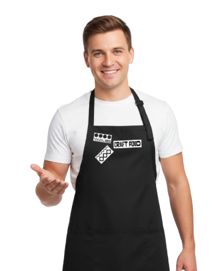 Smiling man in white t-shirt and black apron with 'Craft Food' logo, standing with one hand extended.