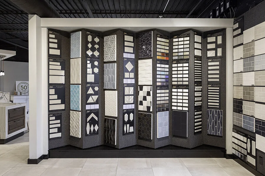 Display of various wall and floor tiles in different colors and patterns at a tile showroom.