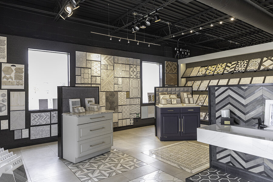 Interior of a tile showroom displaying various tile samples on walls and display stands with a modern aesthetic.