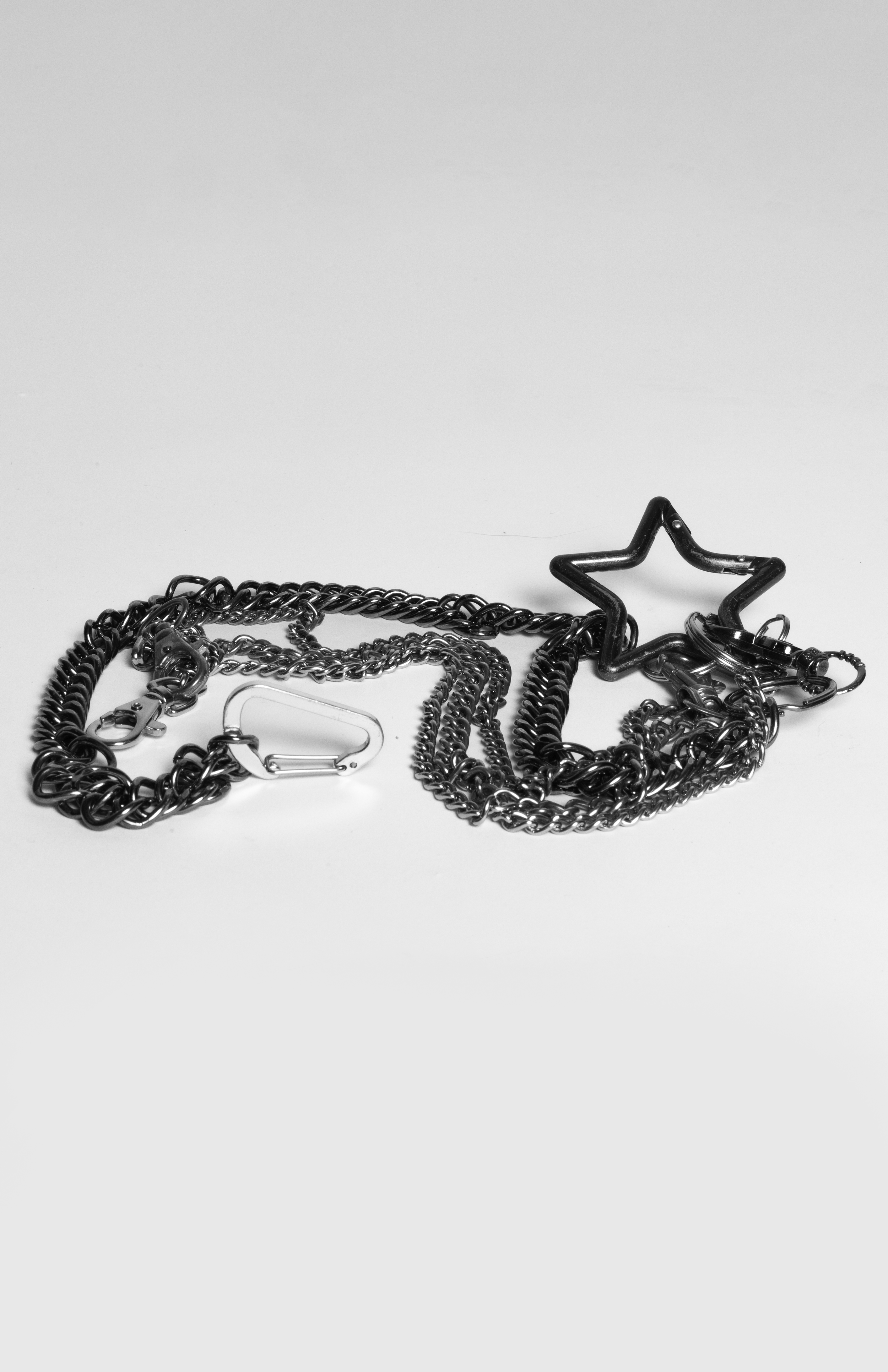 A collection of silver chains and jewelry, including a star-shaped bracelet, arranged on a white background.