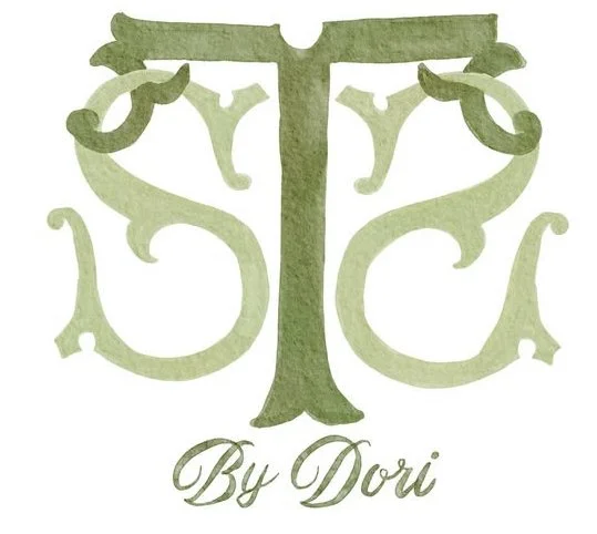 A logo with a stylized green tree and ornamental letters, with the text "By Dori" underneath.