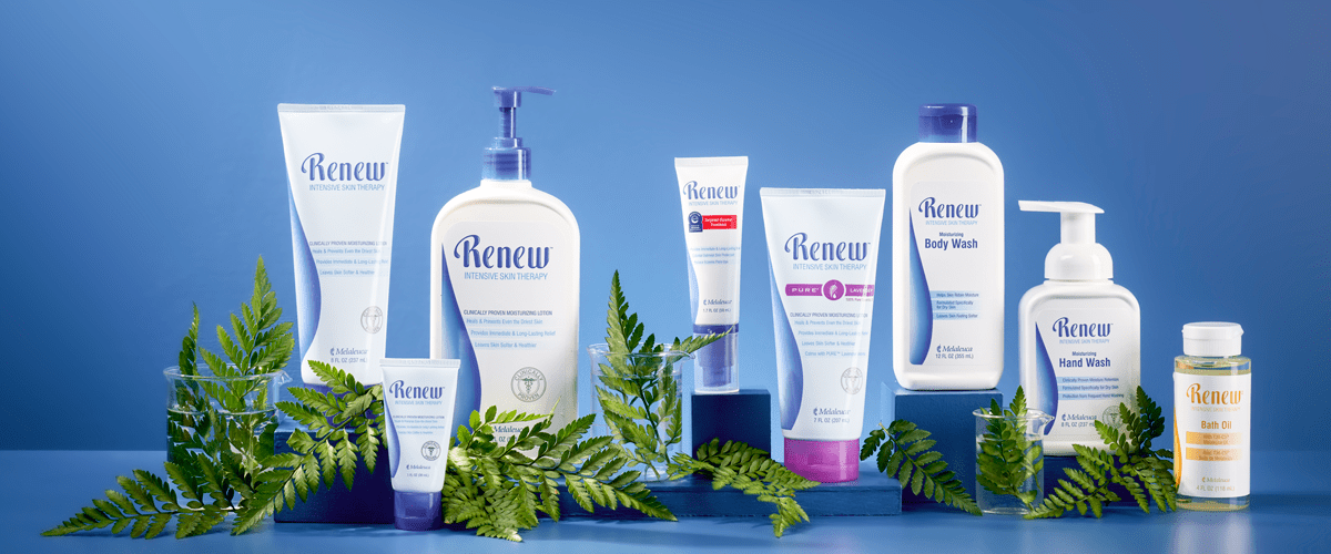 Collection of skincare and hygiene products from the Renew brand, including lotion, body wash, hand wash, bath oil, and various creams, arranged with green fern leaves on a blue background.