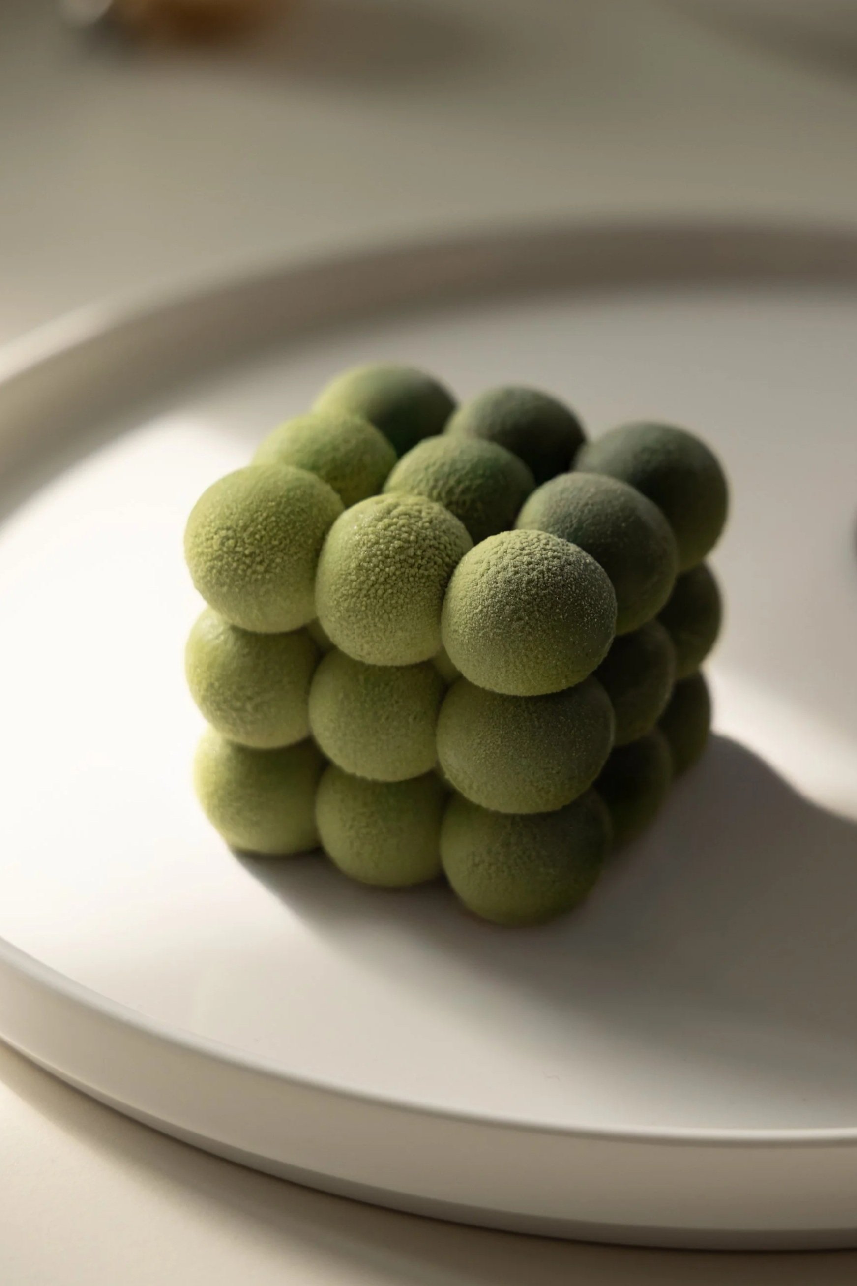 A cluster of green round berries on a white plate.