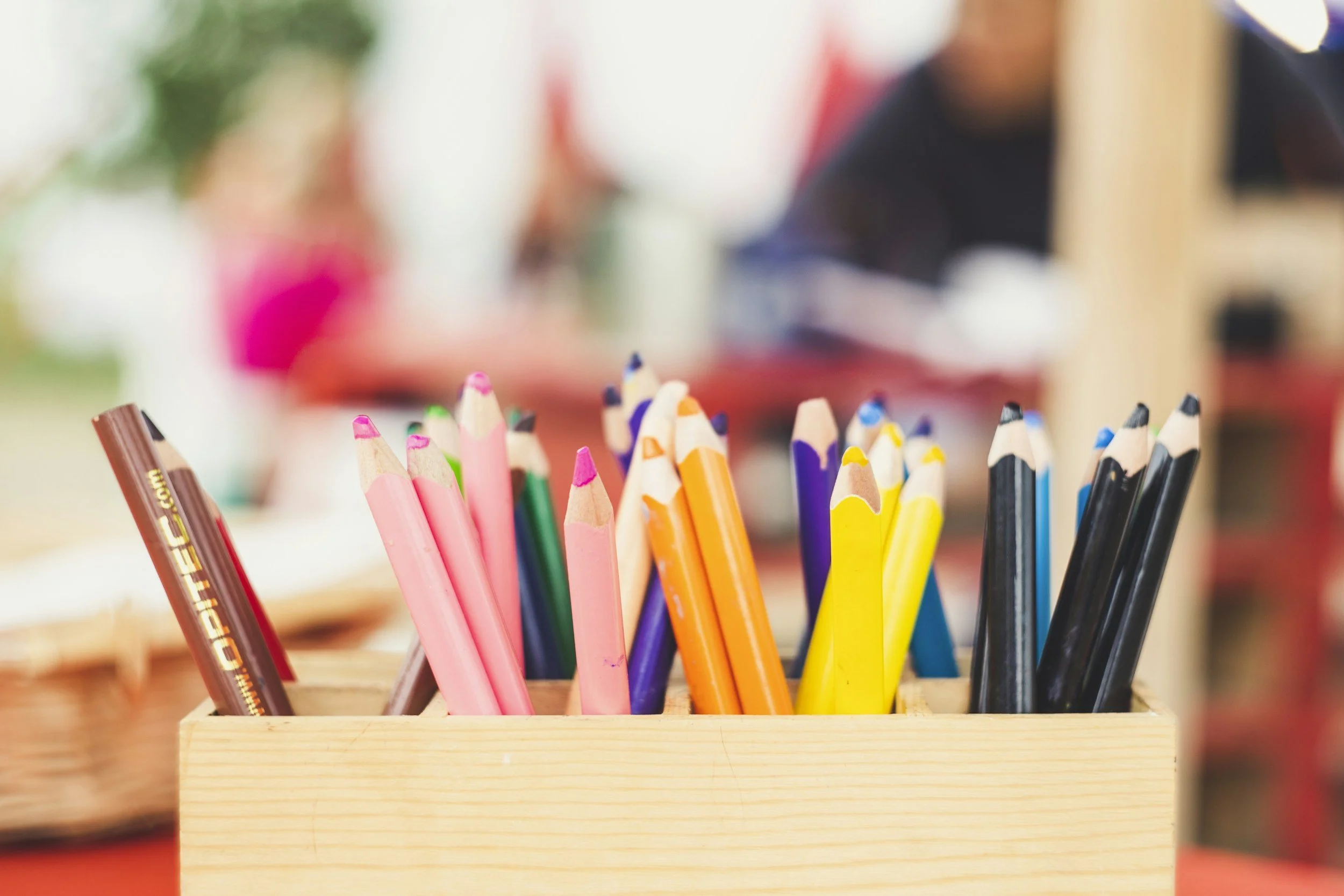 Colorful pencils in a wooden box on a table.
