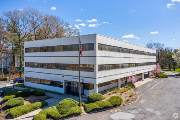 A modern medical office building housing Level One Neurosurgery, featuring large glass windows, landscaped greenery, and an accessible parking area.