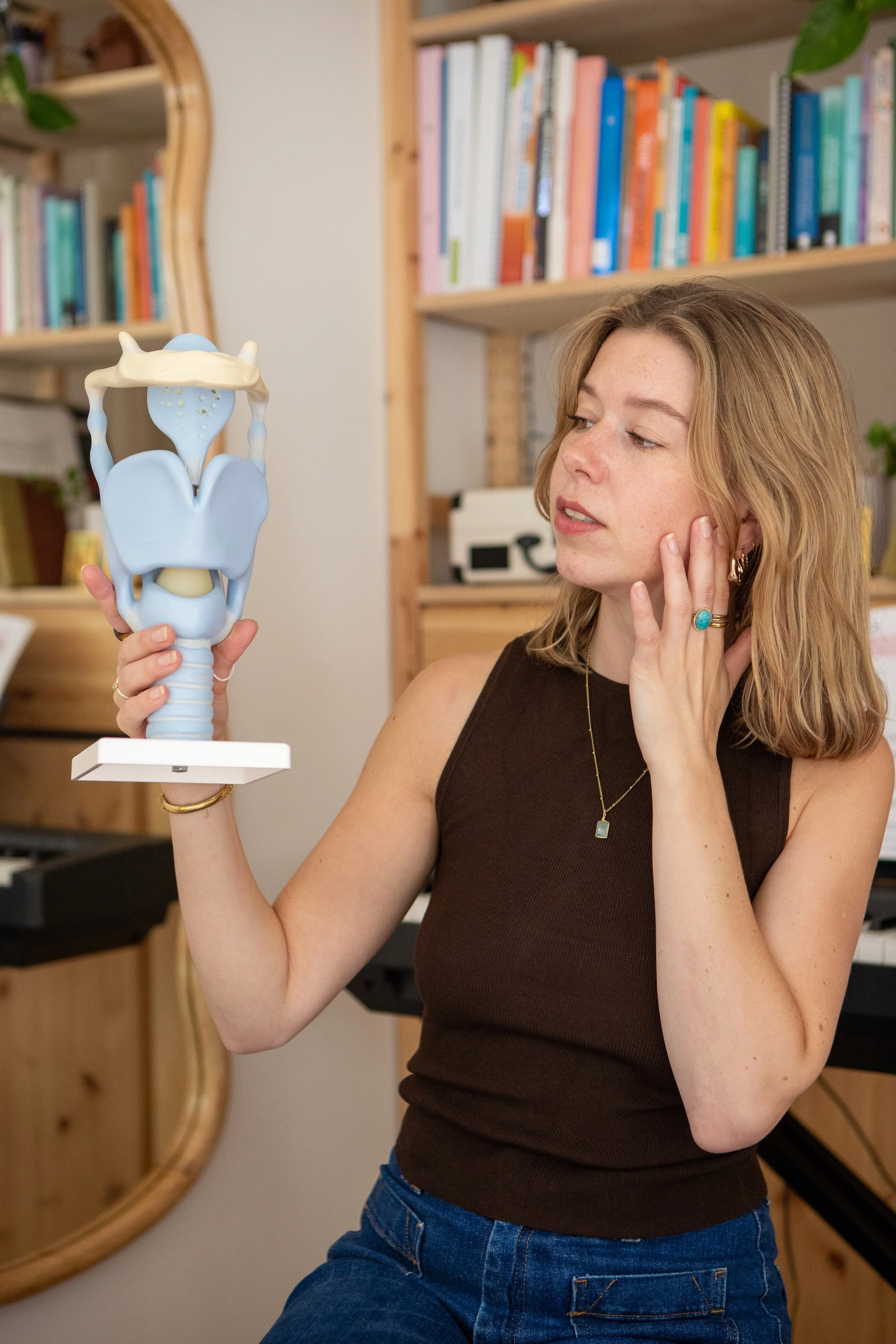 Vrouw met lichtbruin haar die naar een anatomisch model van een menselijk lichaam kijkt.