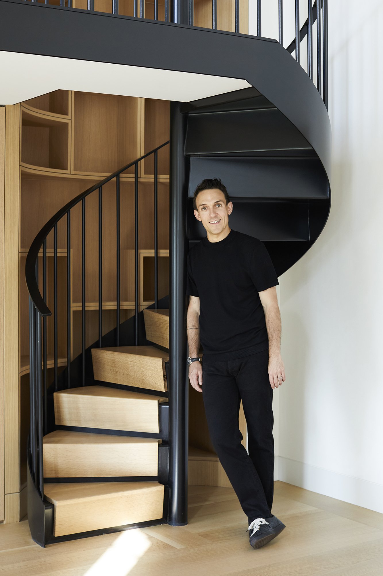 Estudio Esmero principal, Juan Jofre Lora, stands in front of a custom spiral staircase at one of the newly completed projects by the office.