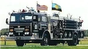 A vintage fire truck with flags on top, parked on grass, labeled 'Firewood Lake'.