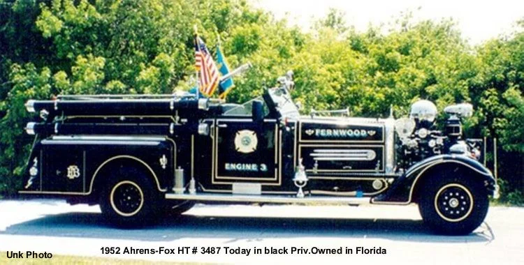 A vintage 1952 Ahrens-Fox fire truck in black with gold trim, labeled 'Engine 3', parked outdoors with green trees in the background. It has American flags on top and is privately owned in Florida.