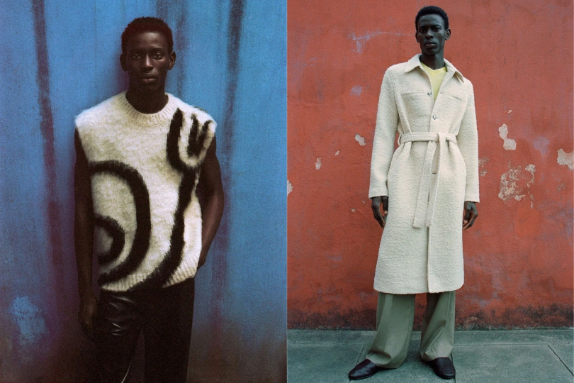 Two models standing against colorful backgrounds. The left model wears a sleeveless sweater with black and white abstract patterns, dark pants, and stands in front of a blue wall. The right model wears a long, cream-colored coat with a belt, green wide-leg pants, black shoes, and stands against a red wall.