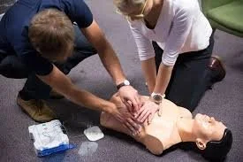 Two people performing CPR on a medical training mannequin.
