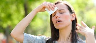 Woman outdoors wiping sweat from her forehead with a cloth