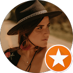 A woman wearing a wide-brimmed hat decorated with a bow, looking sideways outdoors.