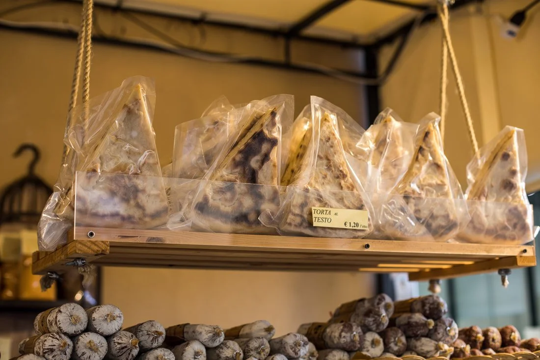 Slices of pizza in plastic bags on a hanging wooden shelf, with garlic bulbs on a lower shelf.
