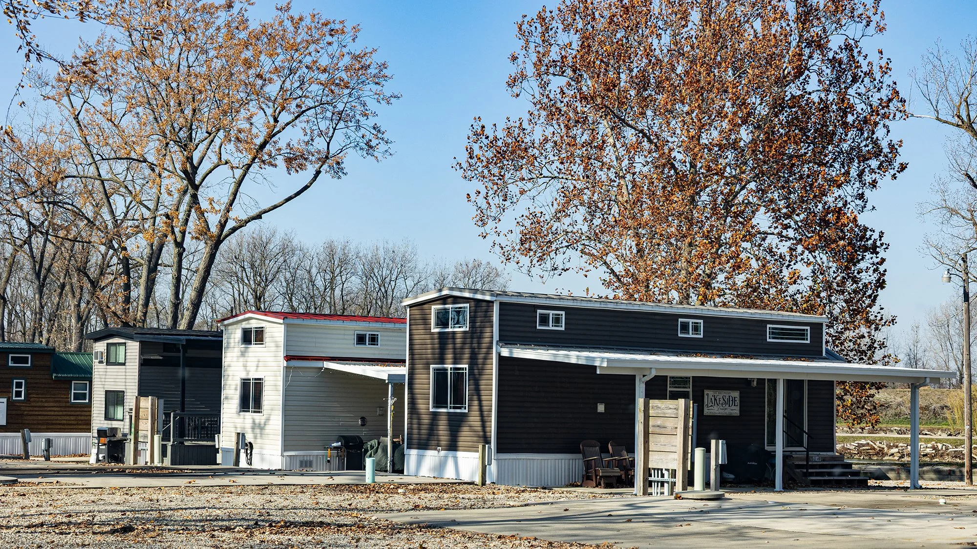 Residential buildings with trees in the background during fall, with leaves on the ground.