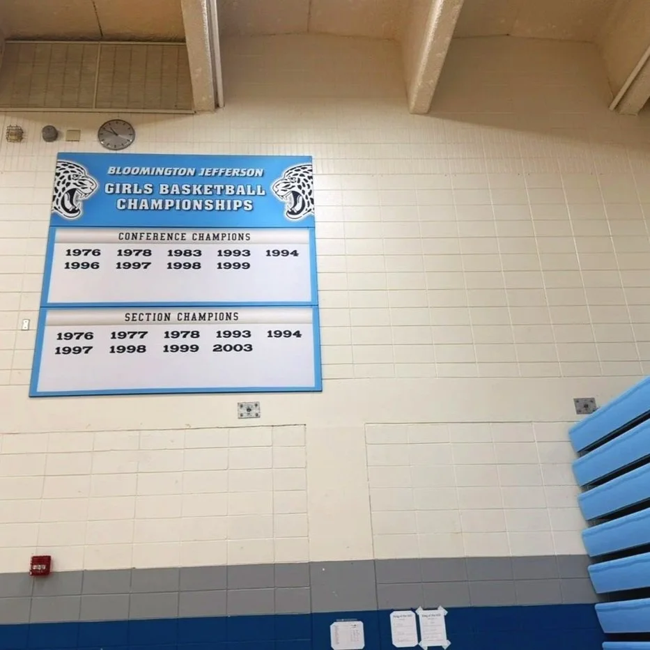 Bloomington Jefferson Girls Basketball Championships banner showing conference and section champions from 1976 to 2003, with logos of jaguars.